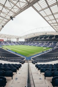 Wide-angle view of a contemporary stadium featuring empty bleachers and a well-maintained grass field, perfect for various sports.
