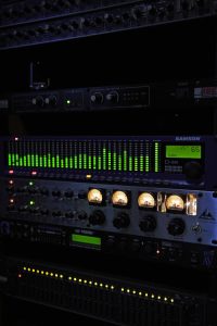 Close-up of professional audio equipment including equalizers and amplifiers in a recording studio.